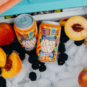 Psychadelic Peach Party cans in a cooler surrounded by peaches, berries, and ice