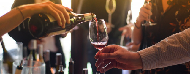 A woman serving a man a glass of whine