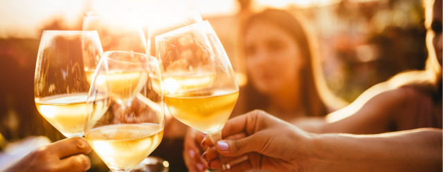 Group of people clinking glasses of white wine.