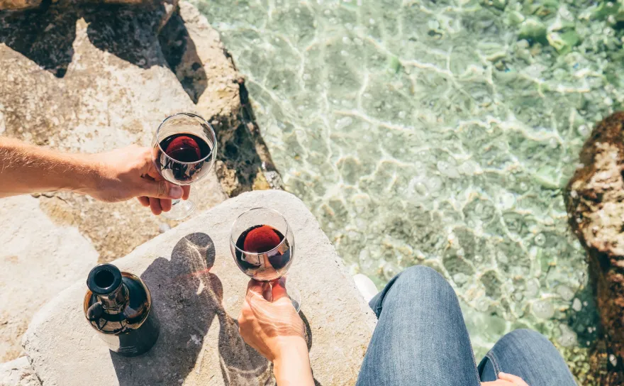 People with wine glasses by water